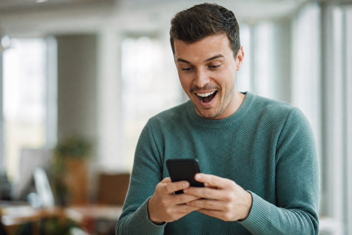 Excited marketer holding cash and checking his phone